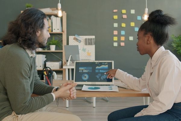Two colleagues discussing data on a laptop screen.