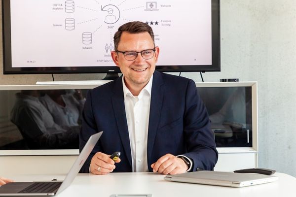 A smiling man in a suit in a modern office.