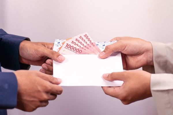 A person is giving money in an envelope.