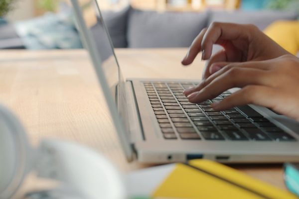 Hands typing on a laptop keyboard at a desk.