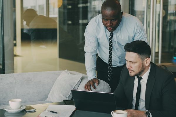 Two businessmen collaborating over a laptop.