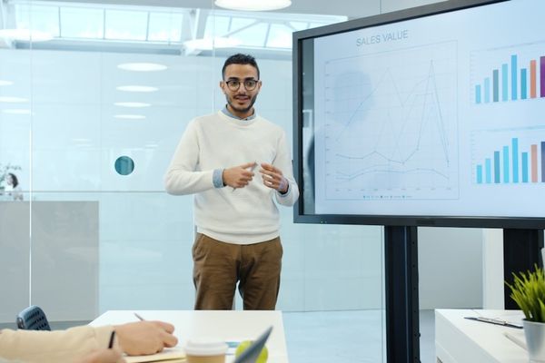 Man presents charts on a screen during a meeting.