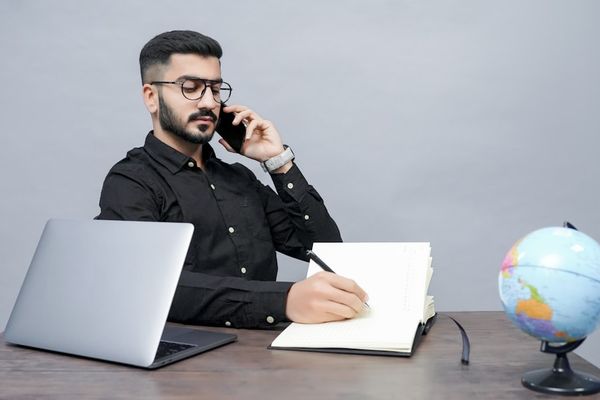 a man holding a pen and a book and a laptop