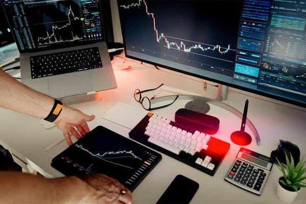 A man sitting at a desk with two monitors and a laptop