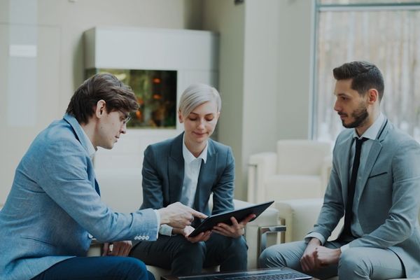 Three professionals discussing a tablet in a modern office.