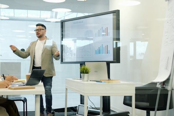 Man presenting data on a large screen to colleagues.