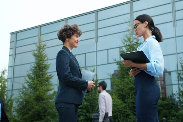 Two businesswomen talking outside modern building