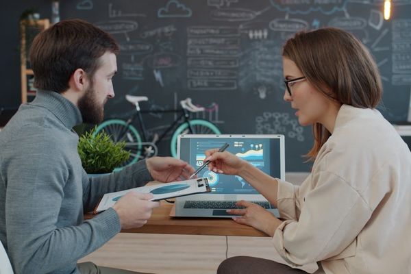 Two colleagues reviewing data on a laptop.