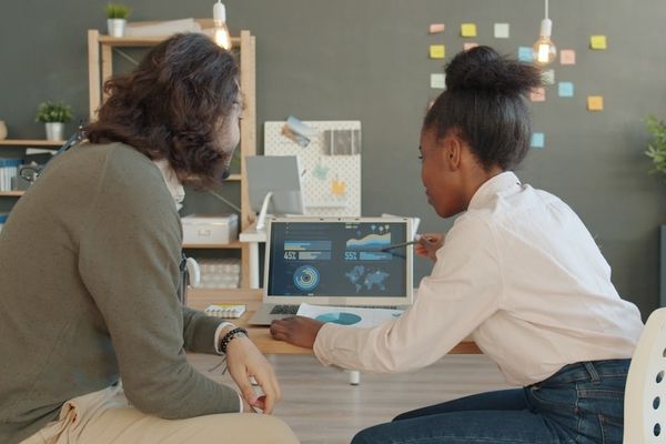 Two people looking at data on a laptop screen
