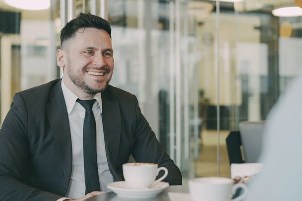 Man in suit smiling at cafe table with coffee