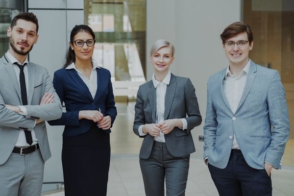 Four professionals in business attire stand together.