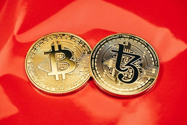 two gold bitcoins sitting side by side on a red cloth