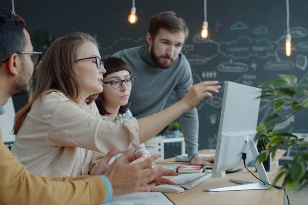 Team collaborating around a computer in an office.