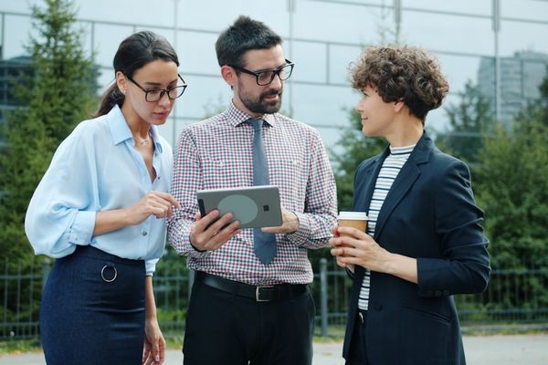 Three colleagues discussing a tablet outside an outdoor setting