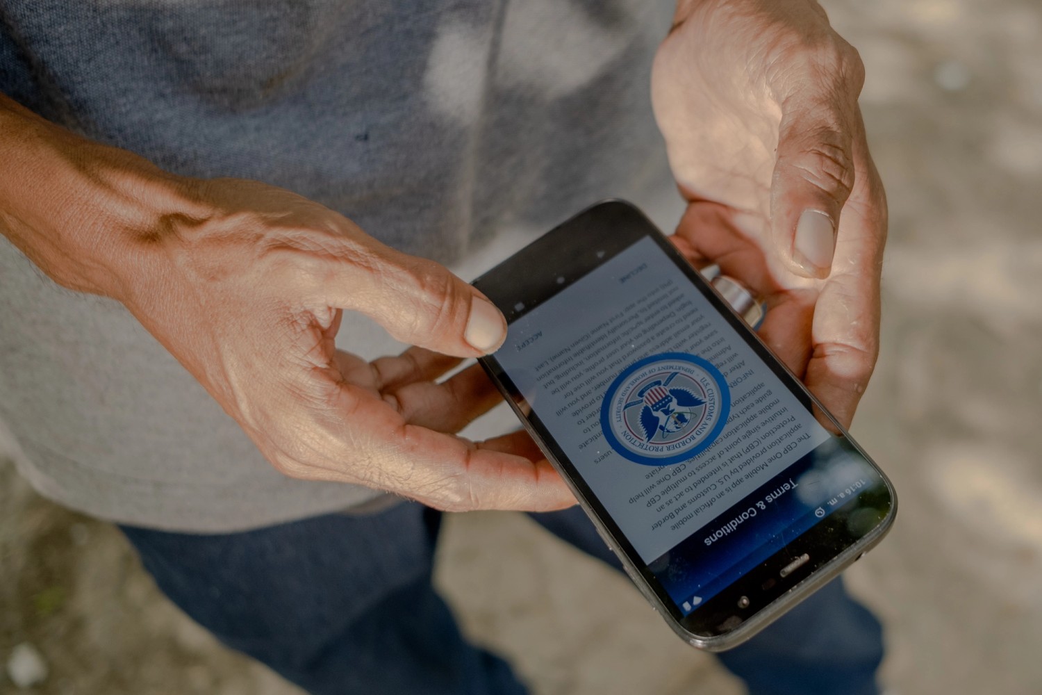 foto de un migrante con su celular intentando registrarse en el sistema migratorio de Estados Unidos