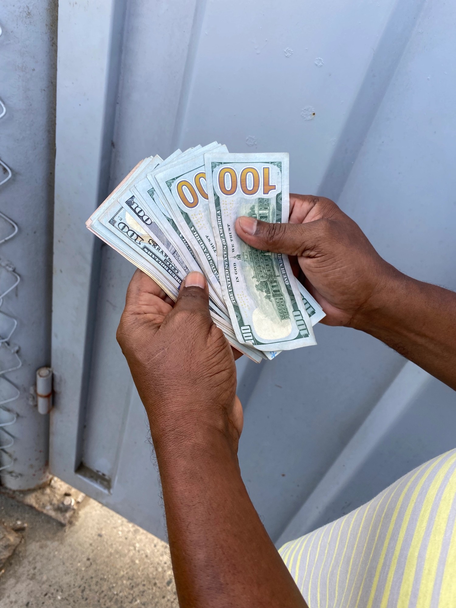 Un traficante de haitianos muestra un fajo de dólares frente al portón fronterizo de Dajabón. 