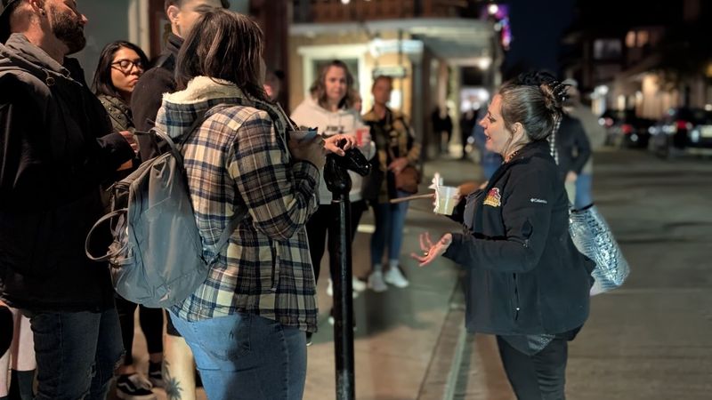 Tour guide animatedly telling stories to attentive group at night