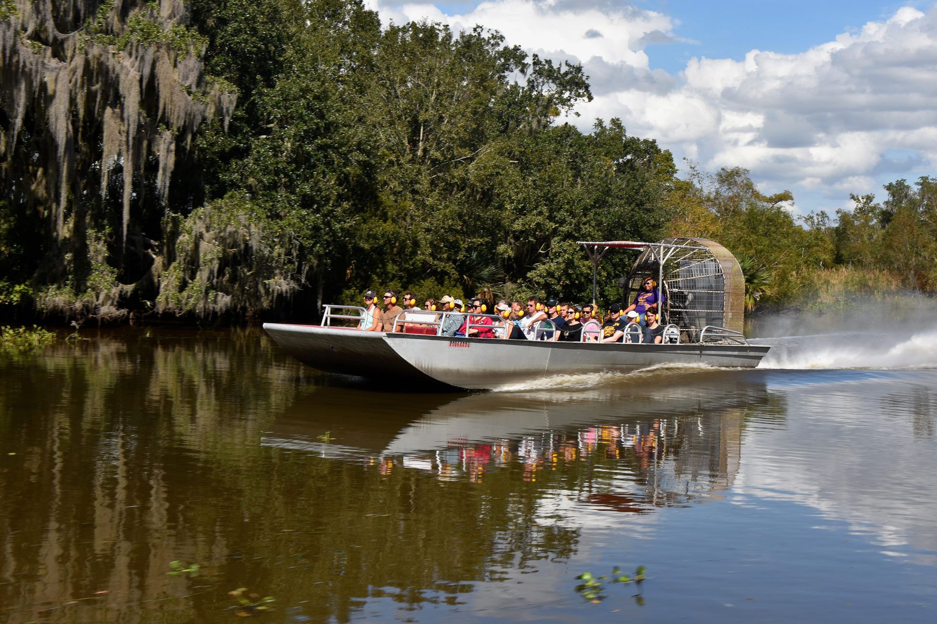 Large 30-passenger airboat cruising through Louisiana cypress swamp with Spanish moss