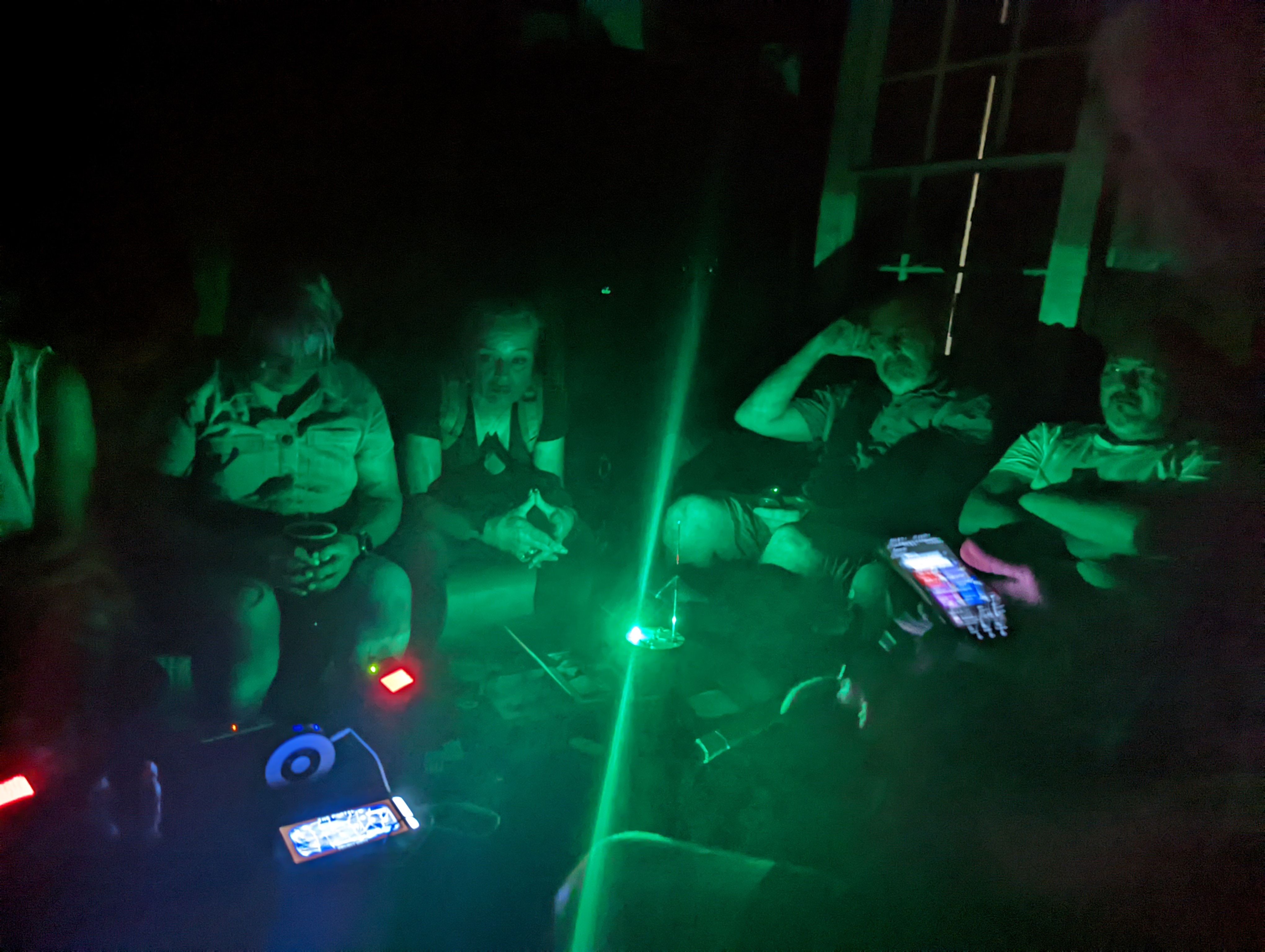 Ghost hunters with green laser grid and EMF equipment in dark room