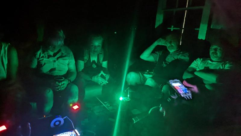 Ghost hunters with green laser grid and EMF equipment in dark room