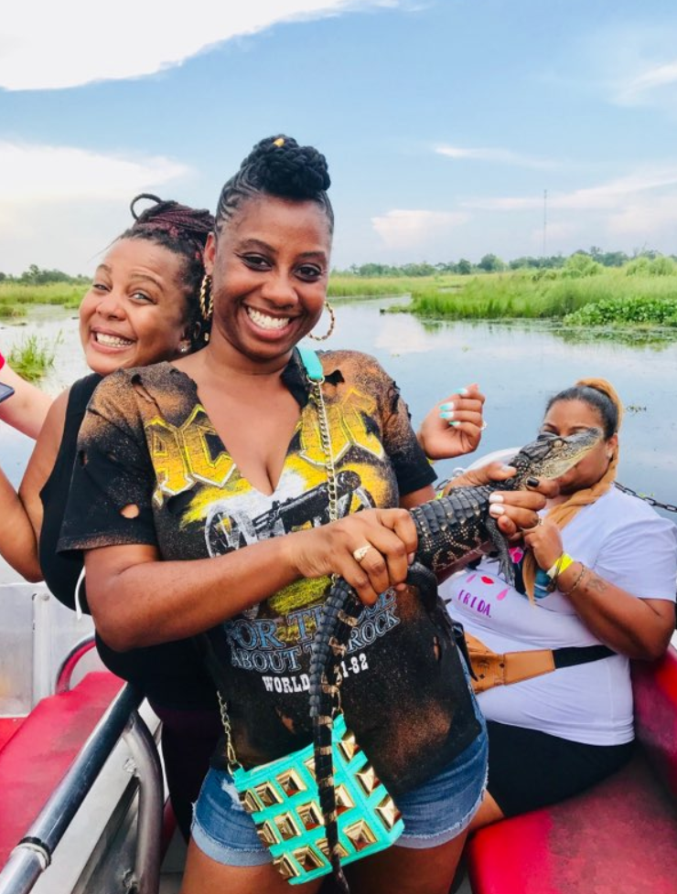 Guests laughing while holding a baby alligator on the airboat swamp tour
