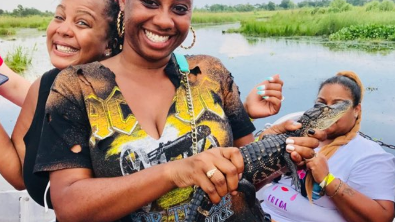Guests laughing while holding a baby alligator on the airboat swamp tour