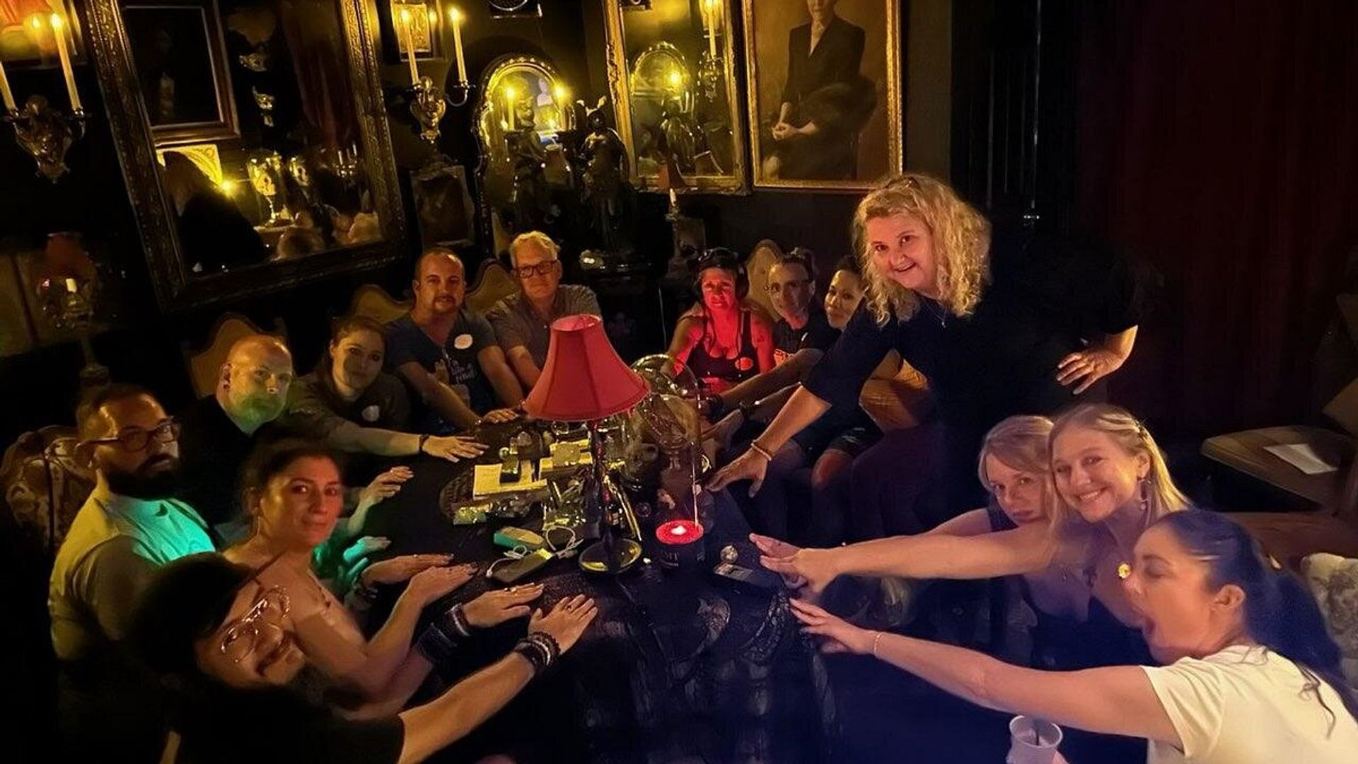 Group participating in seance around candlelit table with Victorian decor