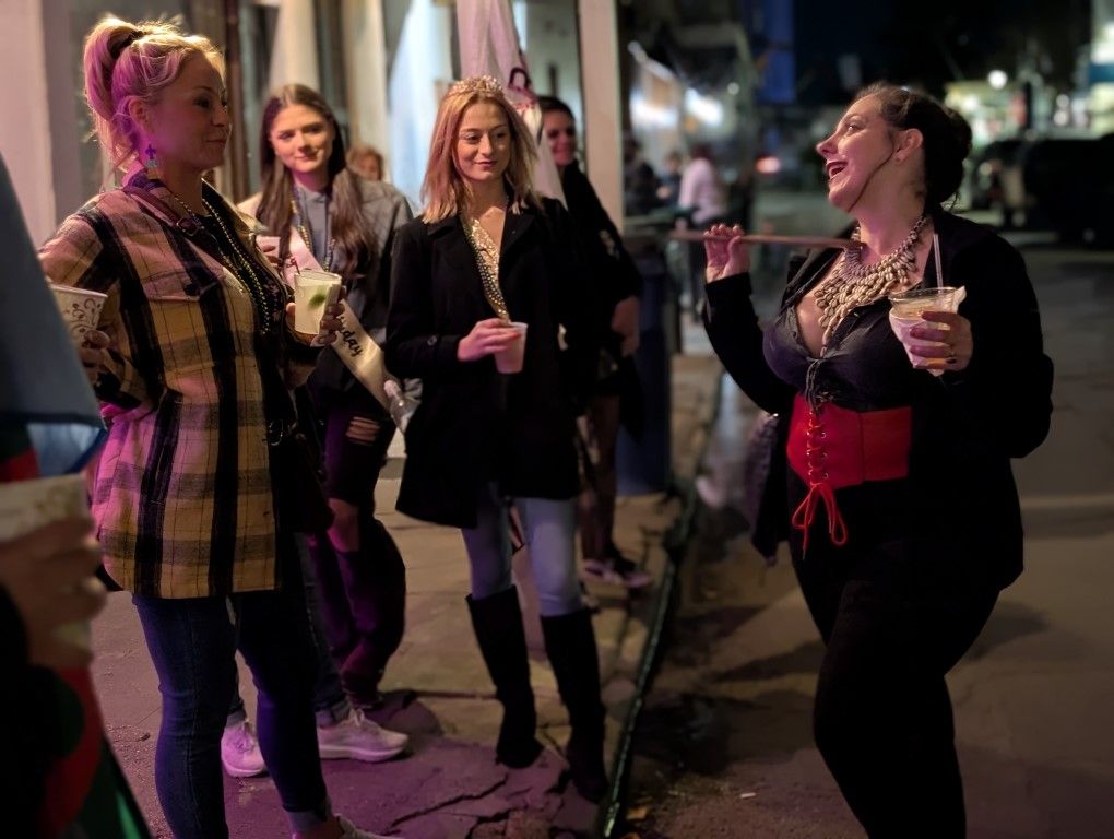 Guide in corset leading bachelorette party group with drinks