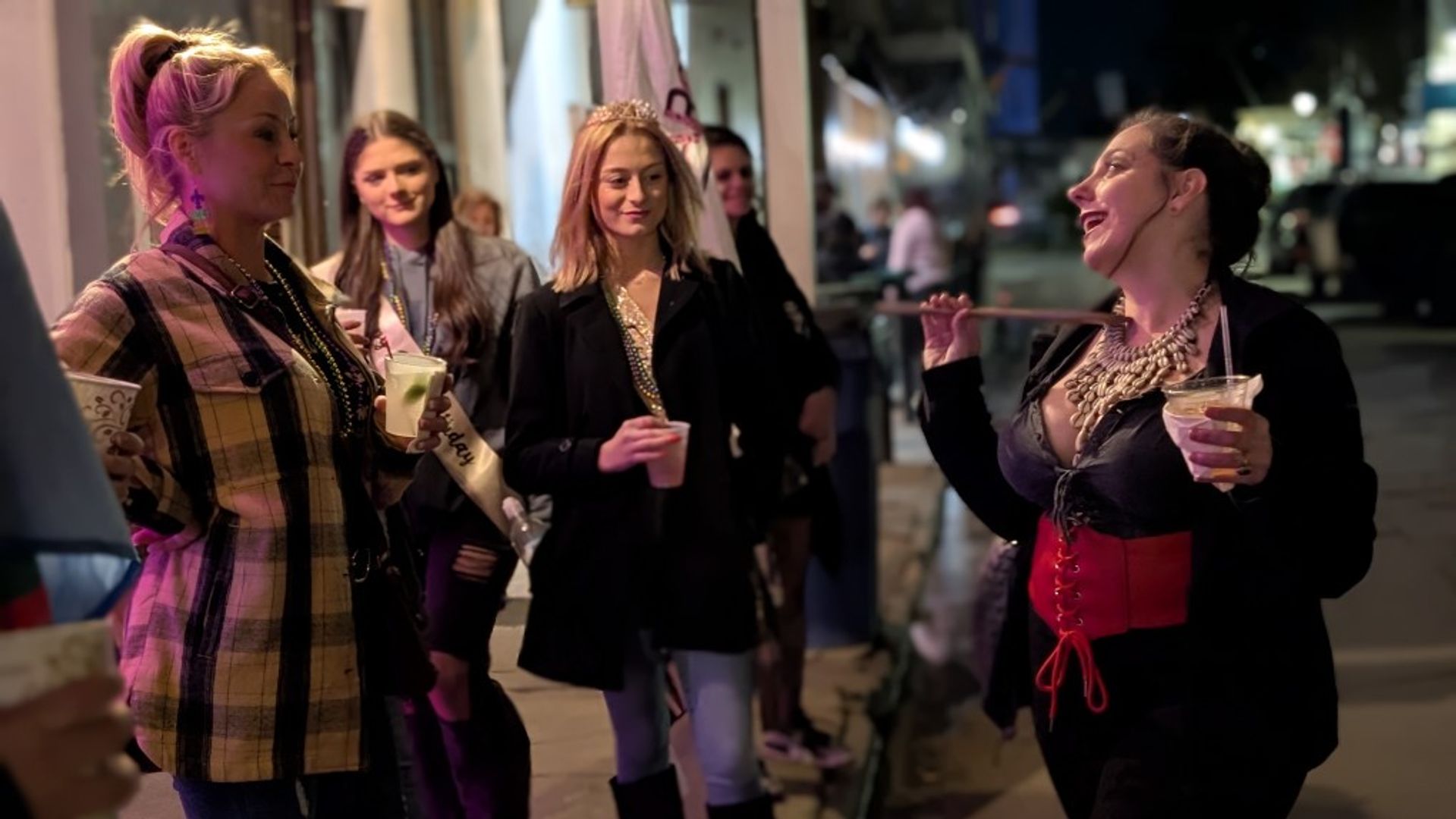 Guide in corset leading bachelorette party group with drinks