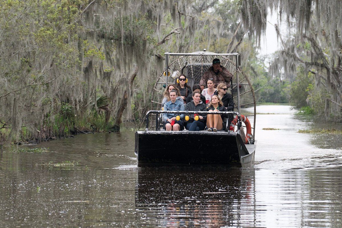 Small 10-seat airboat cruising through Louisiana swamp waterway