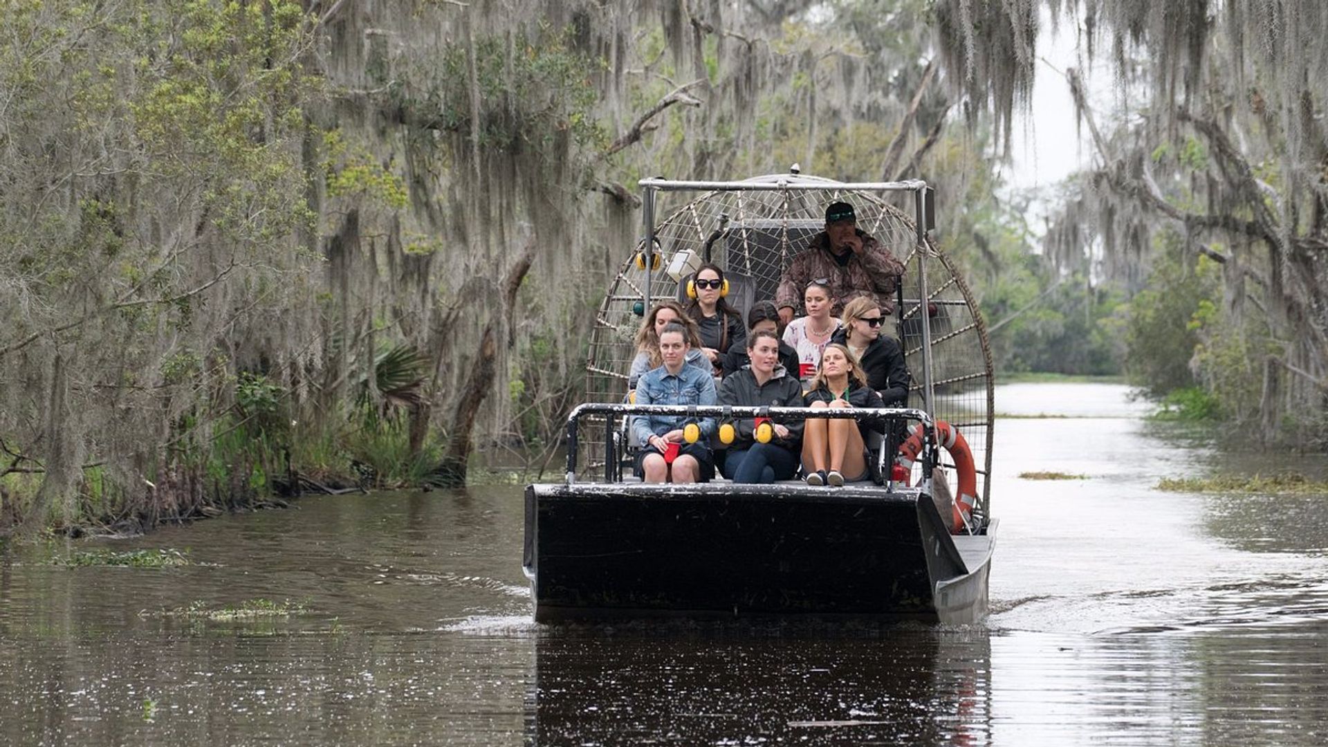 Small 10-seat airboat cruising through Louisiana swamp waterway