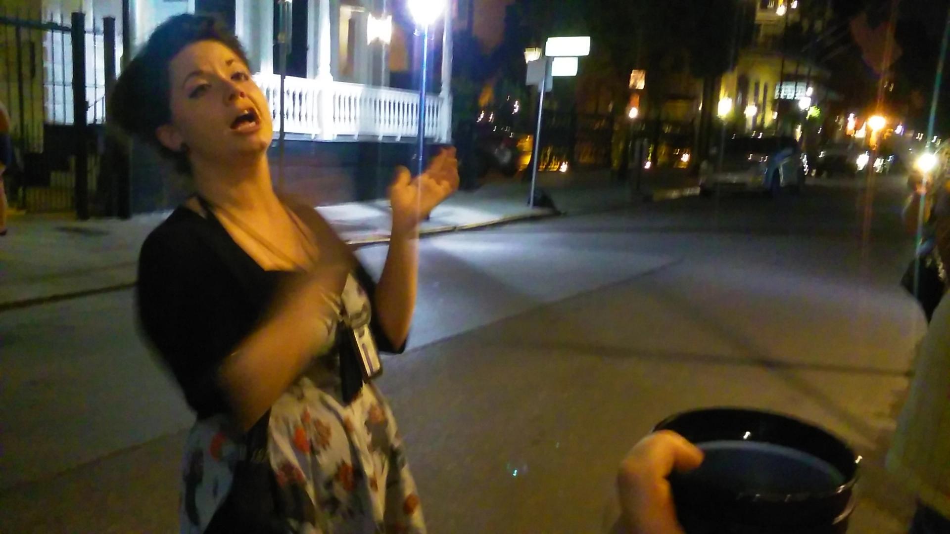 Expressive tour guide mid-story on New Orleans street at night