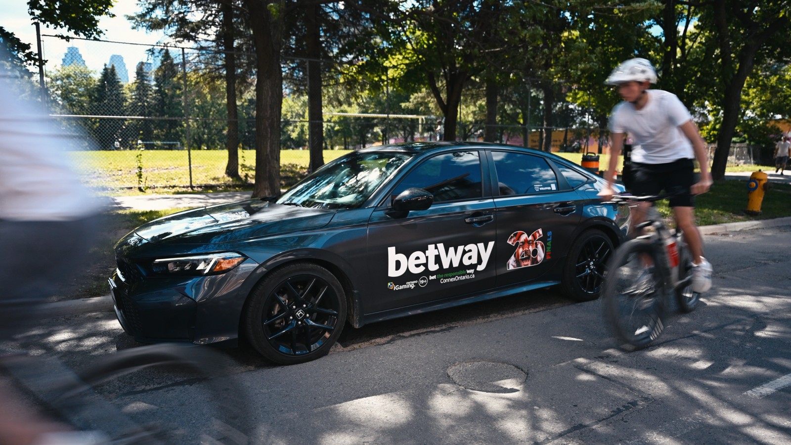 Betway wrapped sedan beside a Toronto cycling route