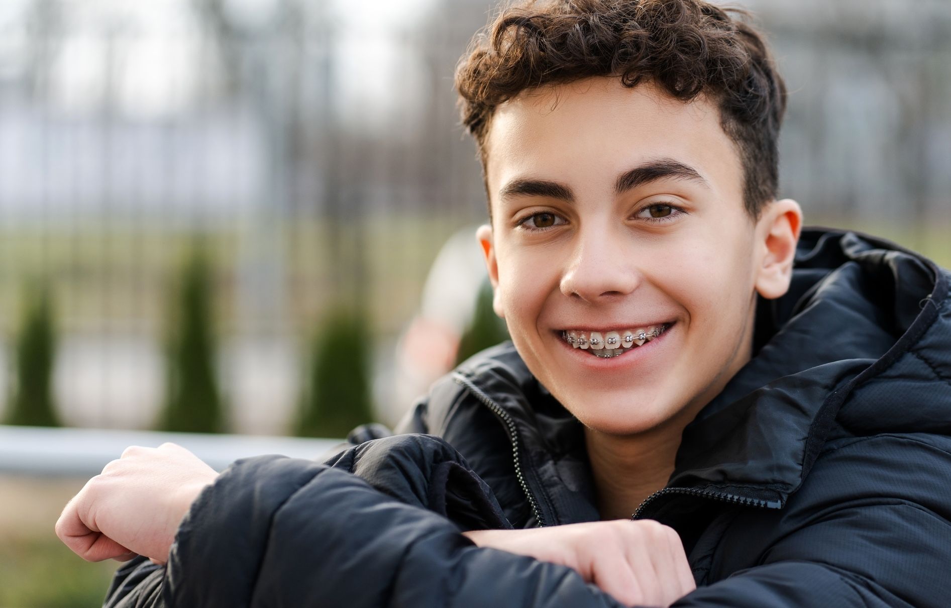 A teenager with fixed braces smiles, soft focus portrait