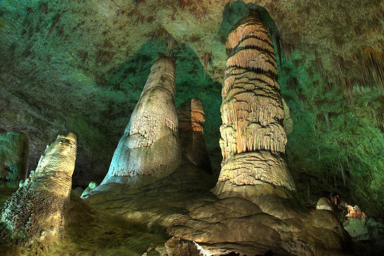 Massive limestone stalagmites rise from the floor of Carlsbad Caverns under a ceiling of thin stalactites.