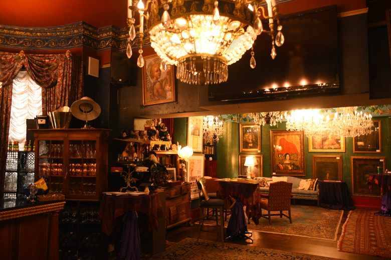 An ornate room in the Mansion on O Street filled with crystal chandeliers, framed portraits, and antique furniture.