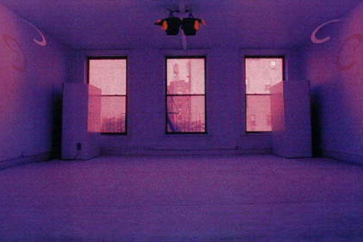 A minimalist room bathed in deep purple light with three windows showing a pink-tinted view of New York City buildings.