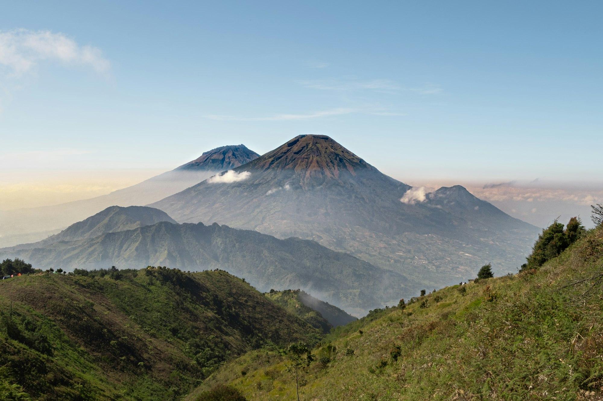 Bukit hijau Dieng dengan latar Sindoro dan Sumbing