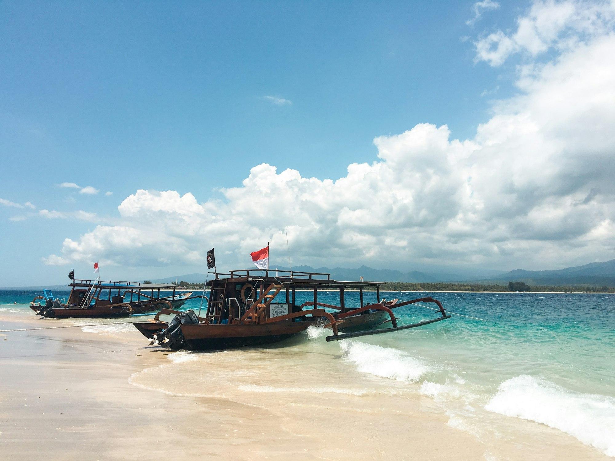 Perahu tradisional di pantai Gili dengan awan putih