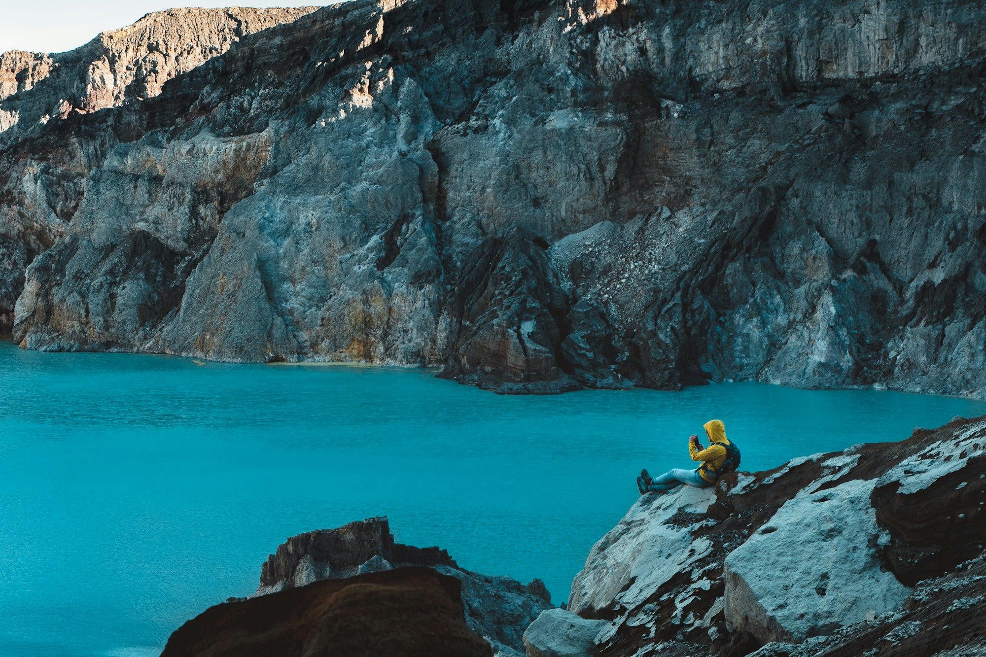 Pengunjung duduk di batu tepi danau kawah Ijen
