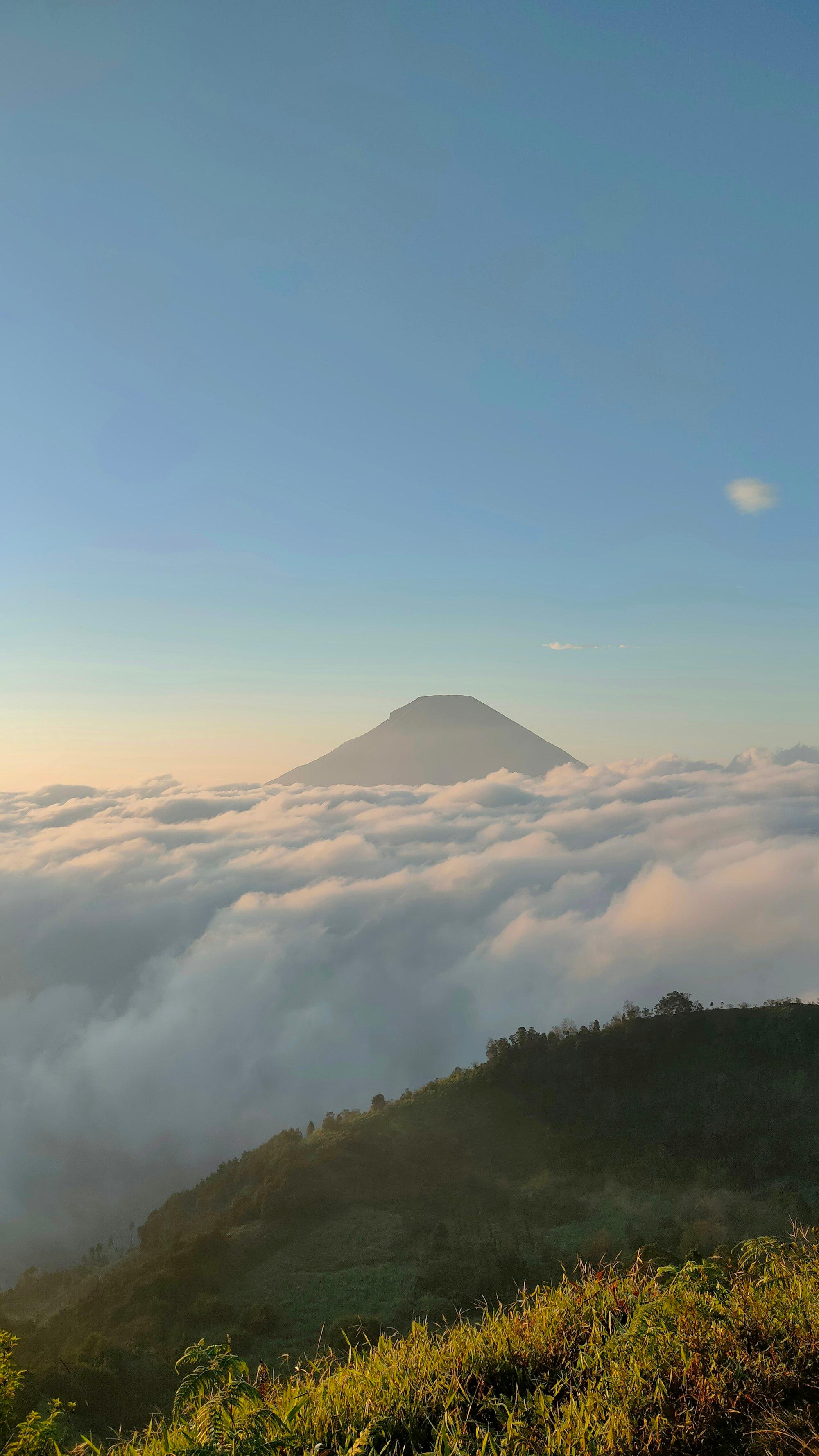 Puncak gunung muncul di atas lautan awan Dieng