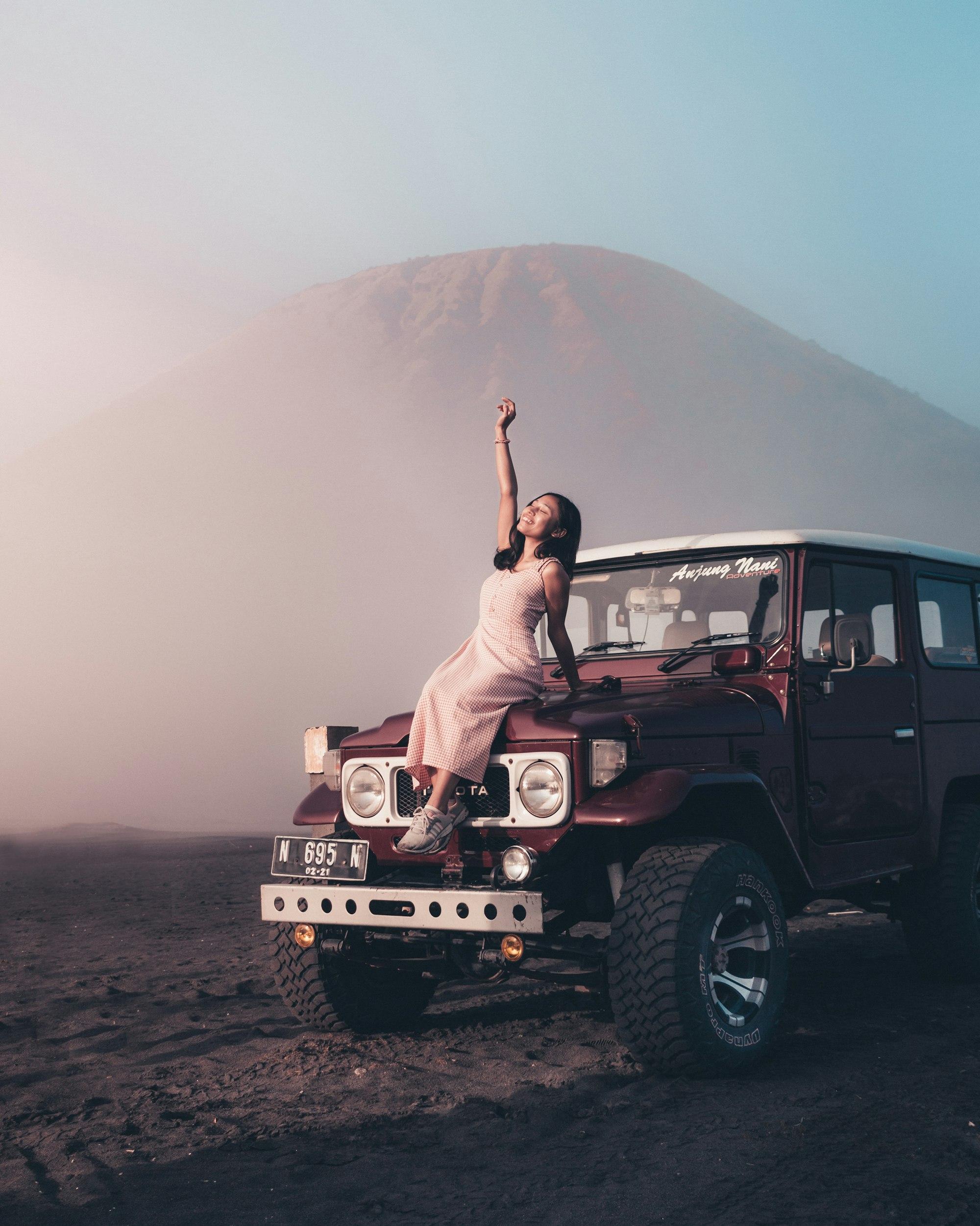 Wisatawan berpose di kap jeep di tengah kabut Bromo