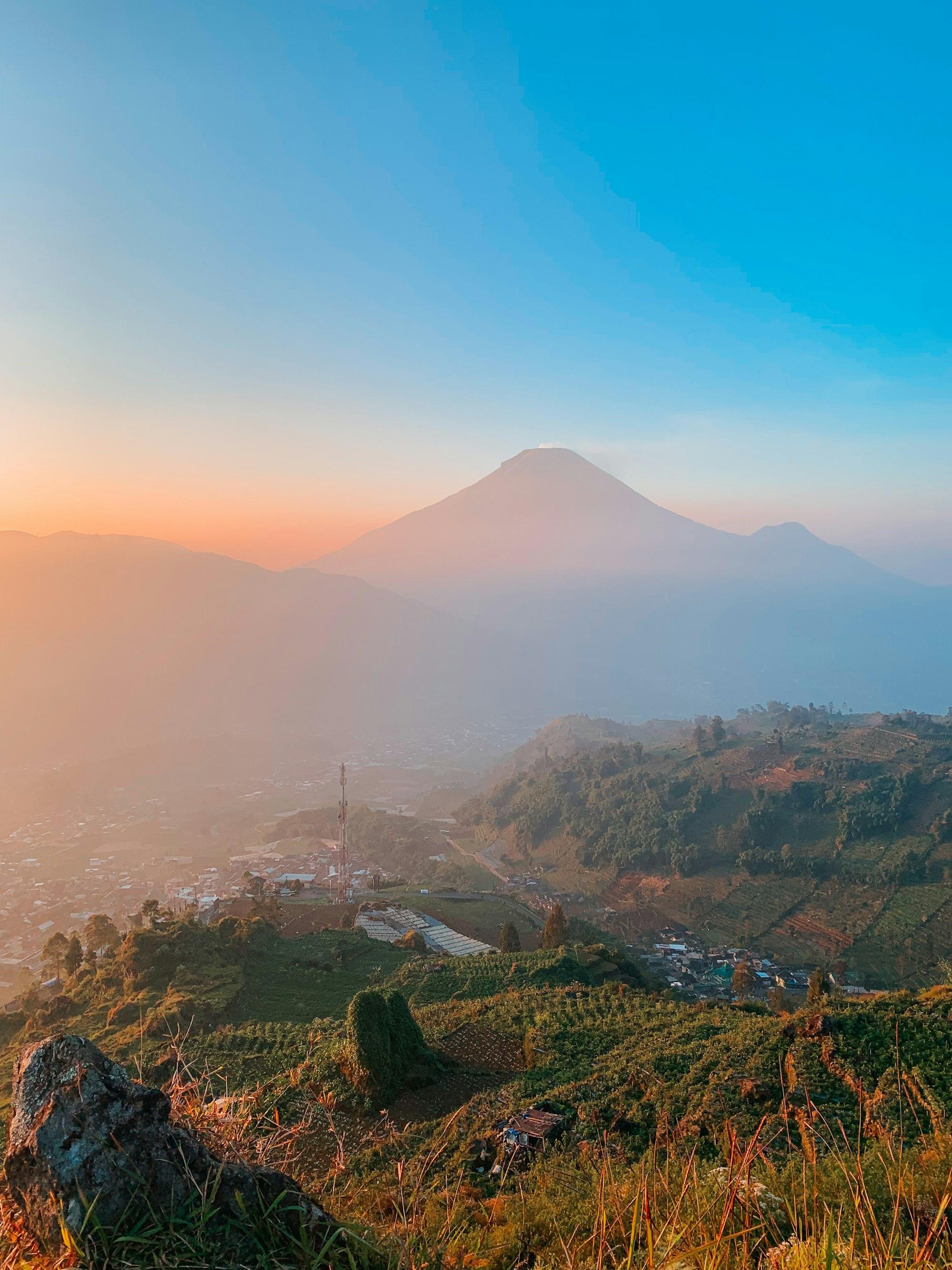 Gunung Sindoro diterpa cahaya jingga pagi dari Dieng