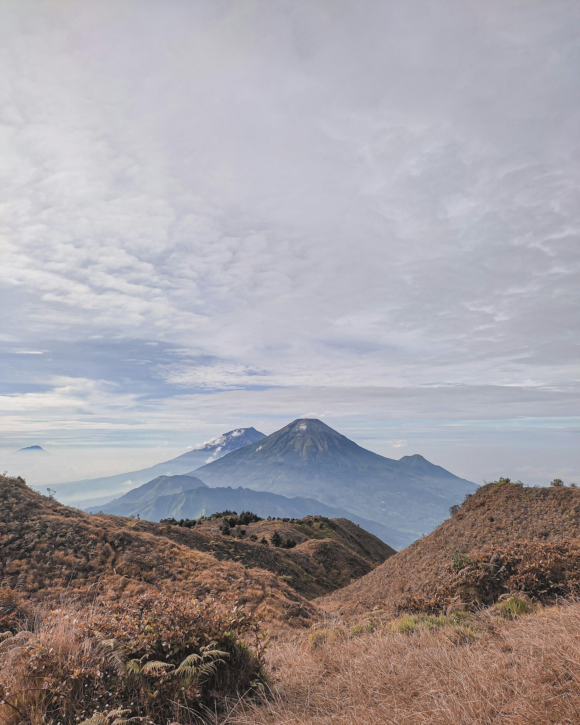 Gunung biru berselimut awan tipis dilihat dari punggungan Dieng