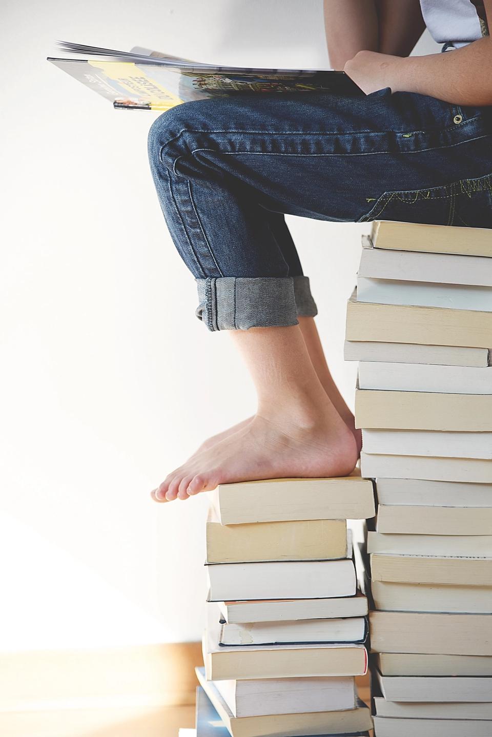 Jeune femme assise sur pile de livres