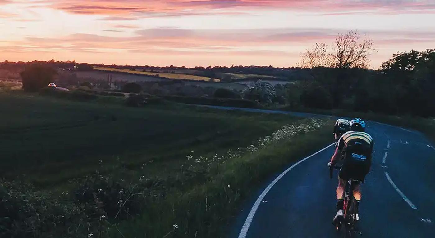 A landscape photograph of a sunset over Whiston with two Club riders up front