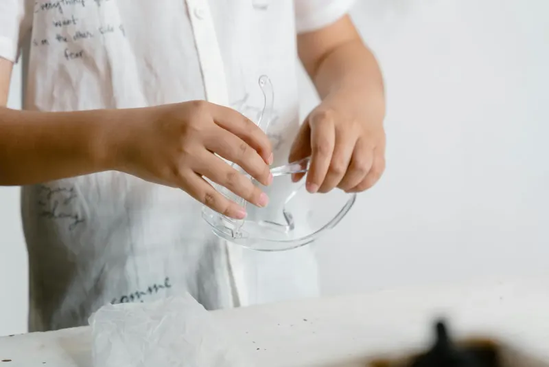 A child carefully holding safety glasses in a close-up photo, emphasizing safety.