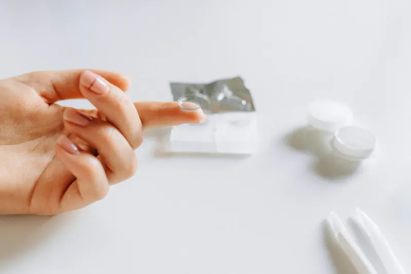 Close-up of hand handling contact lens, demonstrating eye care essentials.