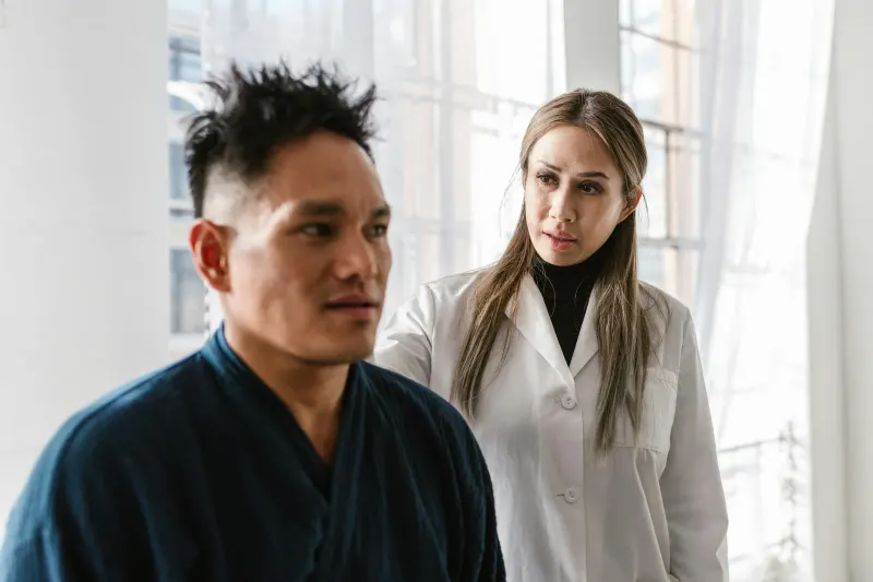 A medical practitioner attentively consulting a patient in a bright indoor clinic setting.