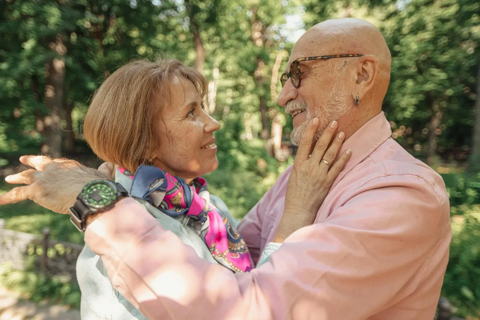 A senior couple shares a loving embrace in a sunlit park, symbolizing togetherness and joy.